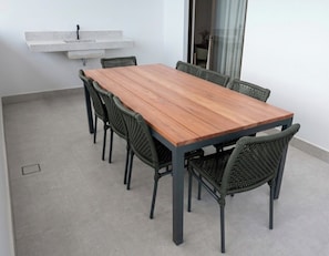 A rectangular wooden table with six chairs, a built-in shelf above, and a glass door leading to a balcony. - BE CAJU FLATS  (Cajueiro da Praia)