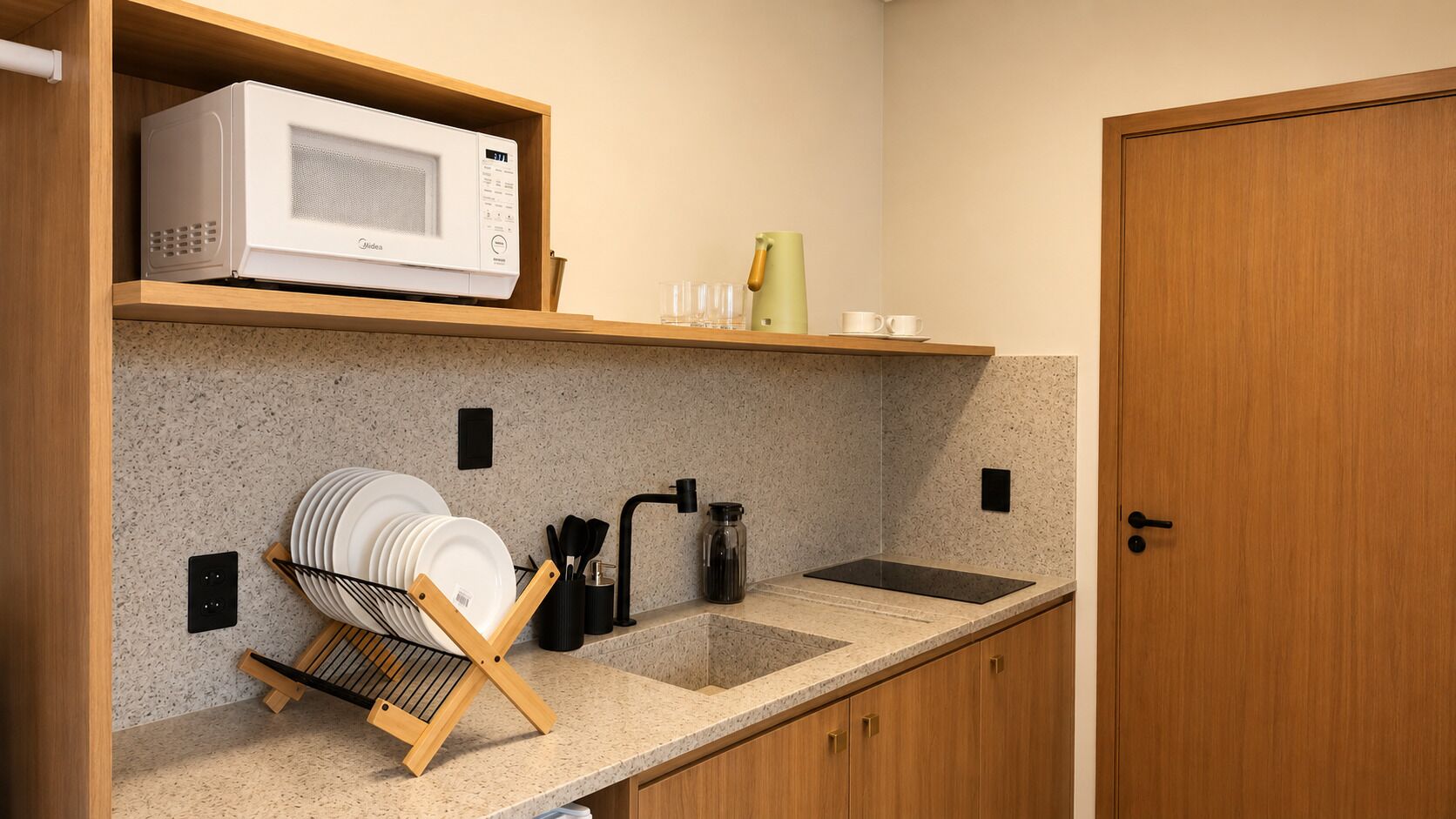 A compact kitchen with a microwave, dish rack, sink, and a cabinet.