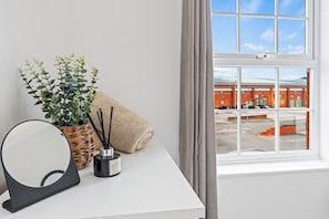 A room with a white desk, a round mirror, a potted plant, a candle, and a towel. - Apartment Sleeps 6 With Parking (Warrington)
