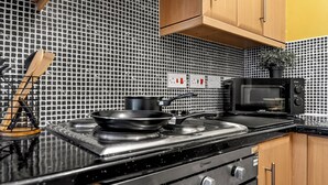 A kitchen with a stove, microwave, and wooden cabinets. - Apartment Sleeps 6 With Parking (Warrington)