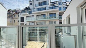 A modern building with a glass balcony, a tiled floor, and a clear sky. - Business Quartier Belvedere (Vienna)