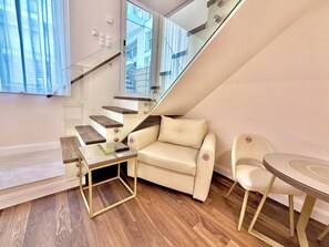 Ein modernes Interieur mit Treppe, Sofa, Tisch und zwei Stühlen.