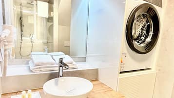 Superior maisonnette | Badkamer | Een douche, een haardroger, handdoeken, zeep