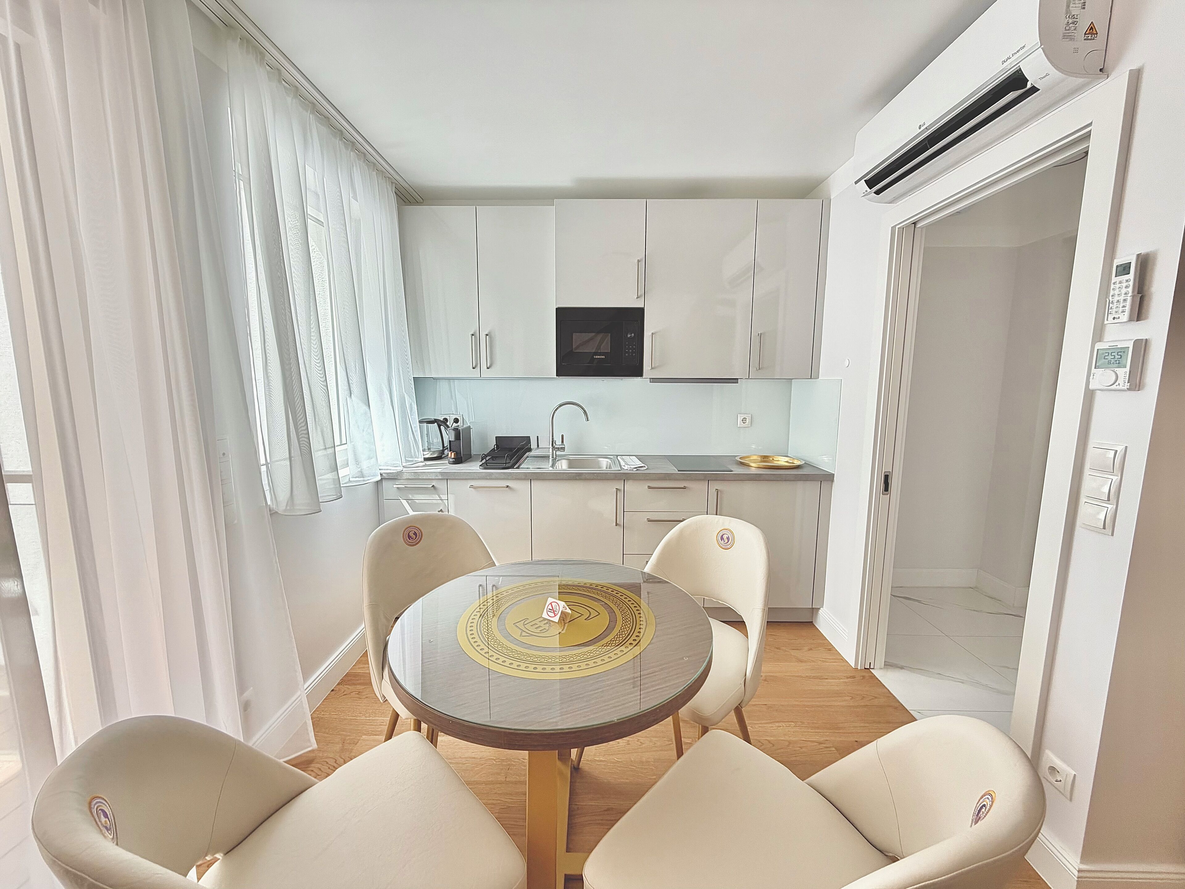 A compact kitchen with a microwave, sink, and dining area with chairs and a table.