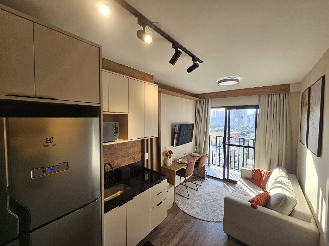 Una cucina moderna con frigorifero integrato, zona pranzo con tavolo e sedie, e un balcone con vista sulla città.