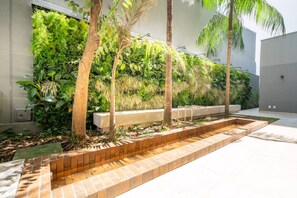 A modern outdoor space with a vertical garden, a brick planter, and a concrete bench. - Studio Bem Localizado - Moema (São Paulo)