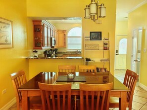 A dining area with a glass-top table and wooden chairs, a kitchen with wooden cabinets, and a welcome sign on the wall. - Stunning 2-bedroom condo in Bodden Town with a free Car!! (Bodden Town)