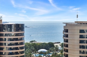 A view of a coastal hotel with a pool area, palm trees, and a beach in the background. - Stylish Marina 1BR with City View, Pool and Gym (Dubai)
