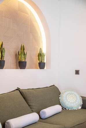 Ein modernes Wohnzimmer mit einer Couch, Kissen, einer Wandpflanzenanzeige und einem gemusterten Kissen.