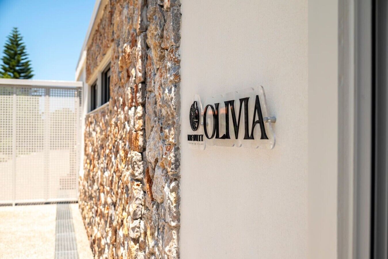 A building facade with a stone wall and a sign that reads 'OLIVIA.'