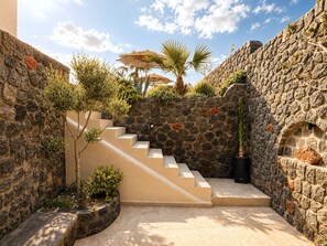 A stone staircase leading to a terrace with a palm tree and a thatched umbrella. - Villa Samaros (Karterádos)