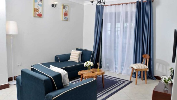 A living room with a sofa set, a chair, a small table, and a lamp. - Beautiful 2-bedroom corporate apartments within  Entebbe (Entebbe)