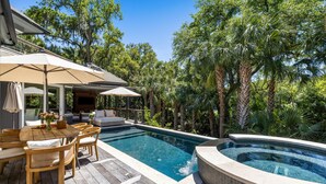 Área de piscina com deck de madeira, espreguiçadeiras e uma banheira de hidromassagem.