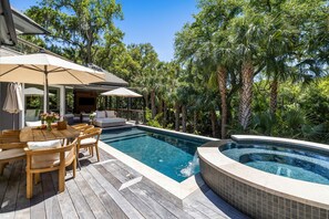 Ein Poolbereich mit Holzterrasse, Liegestühlen und einem Whirlpool.