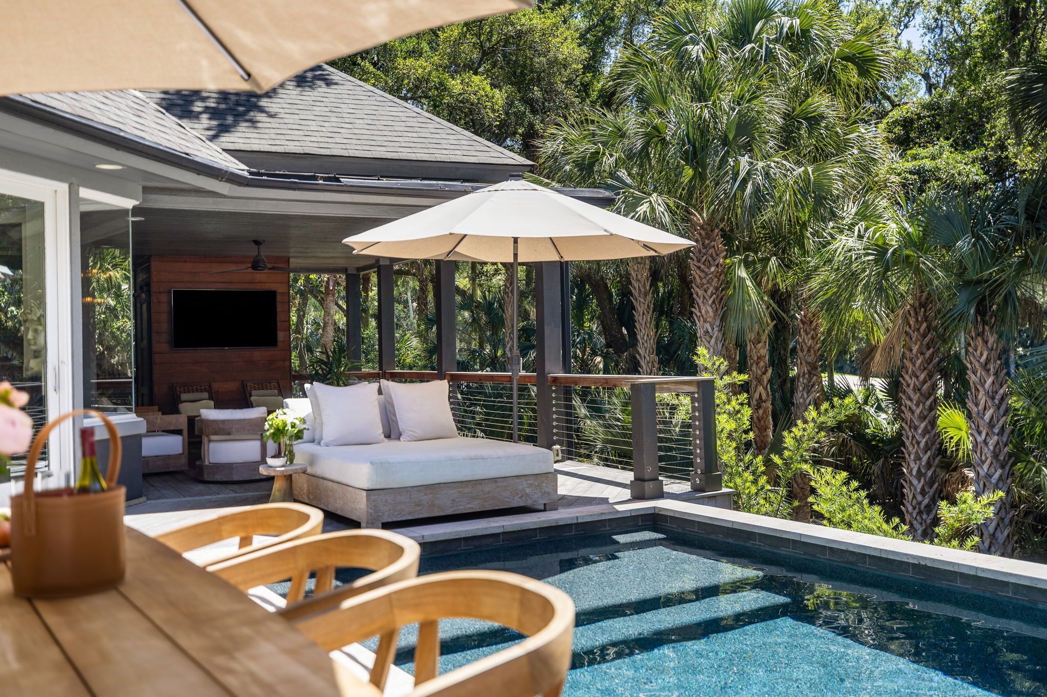 A poolside area with a sofa, chairs, and a TV.