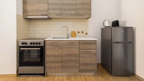 Une cuisine équipée d’un four encastré, d’un évier, de meubles de rangement en bois et d’un réfrigérateur en acier inoxydable.