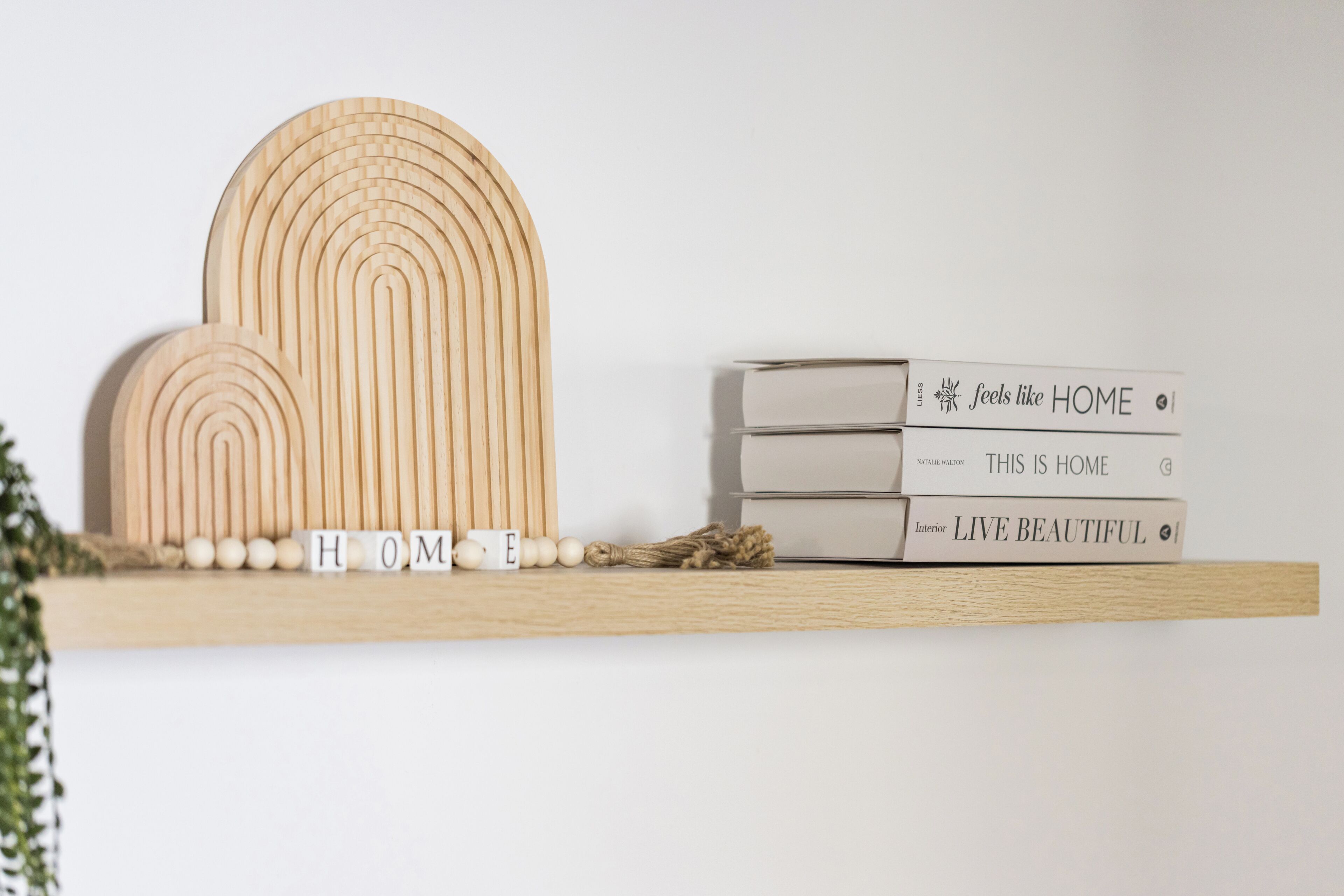 A shelf with wooden geometric shapes, a stack of books, and wooden letter blocks spelling 'HOME'.