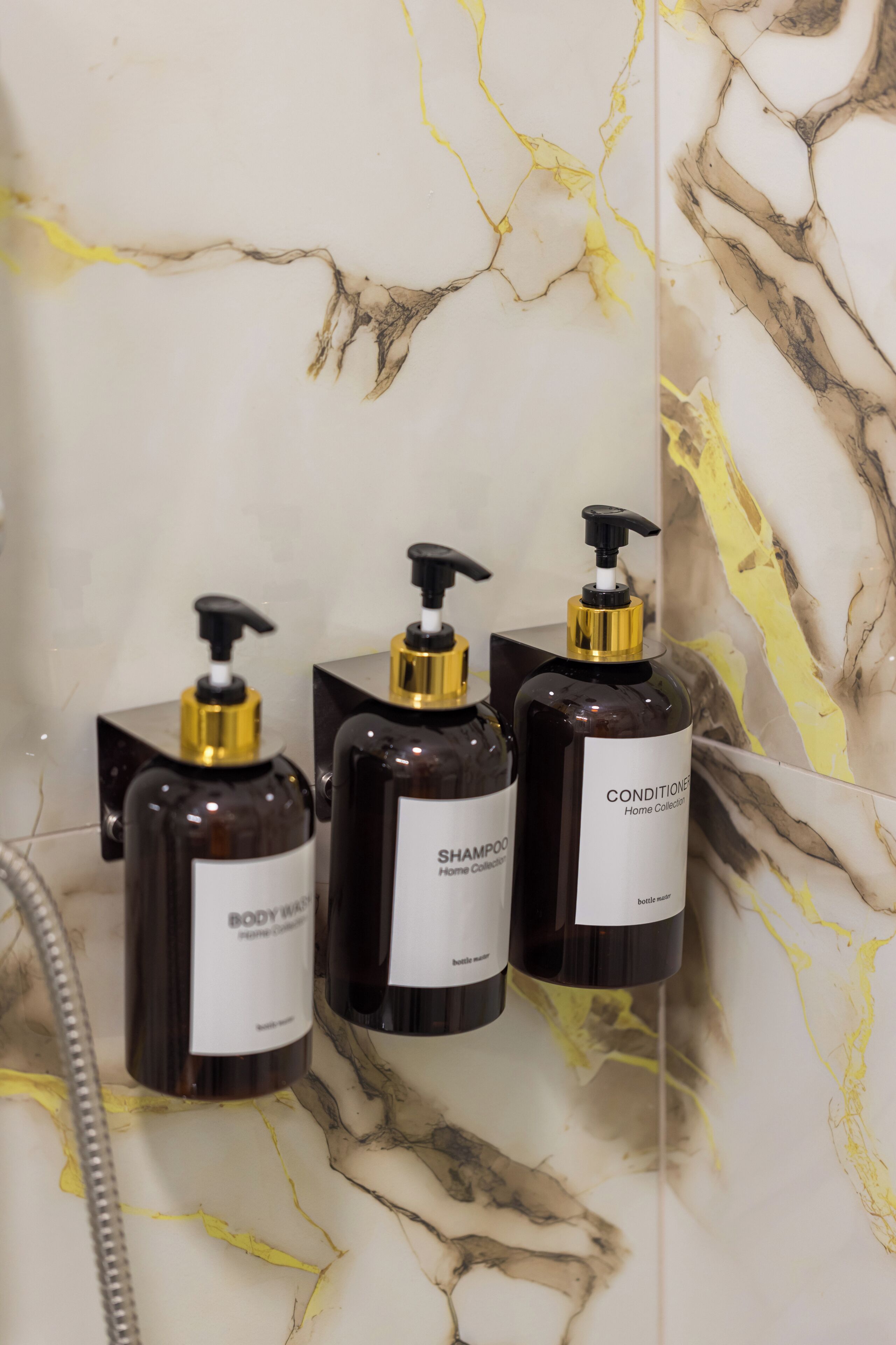 Three bottles of body wash and conditioner on a marble surface.