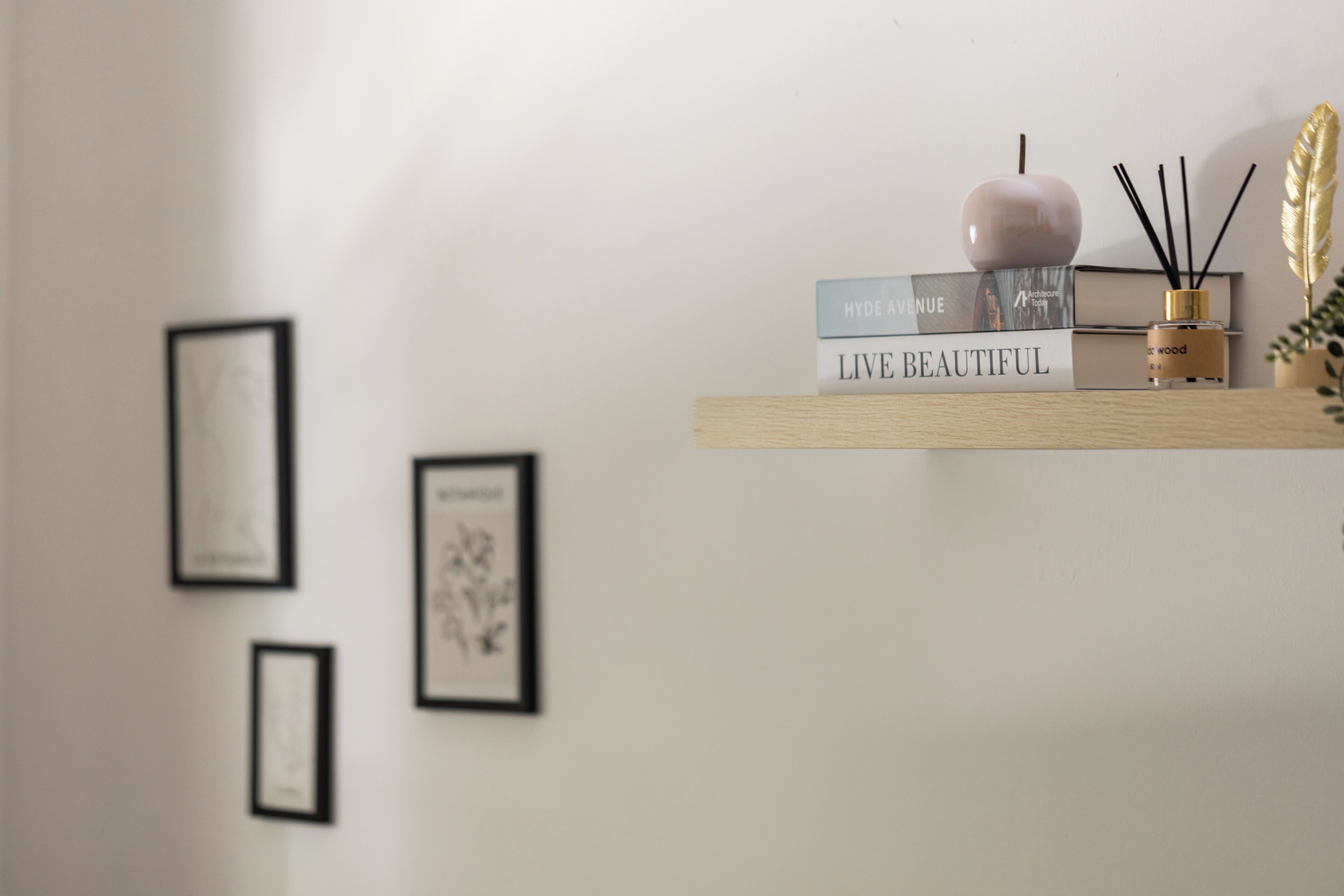 Una estantería con libros, un florero y una botella de aroma a madera.