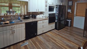Eine Küche mit Holzschränken, einem Geschirrspüler, einem Kühlschrank und einer Mikrowelle.