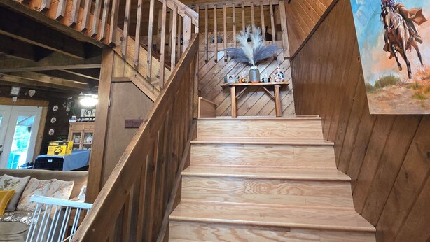 Eine Holztreppe mit Deckenventilator, einem Gemälde eines Cowboys zu Pferde und einem kleinen Tisch mit Dekorationen.