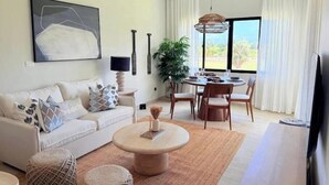 A living room with a sofa, coffee table, and dining area with chairs and a table. - C5 -307 VISTA CANA / Panorama Lake (Punta Cana)