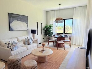 A living room with a sofa, coffee table, and dining area with chairs and a table. - C5 -307 VISTA CANA / Panorama Lake (Punta Cana)