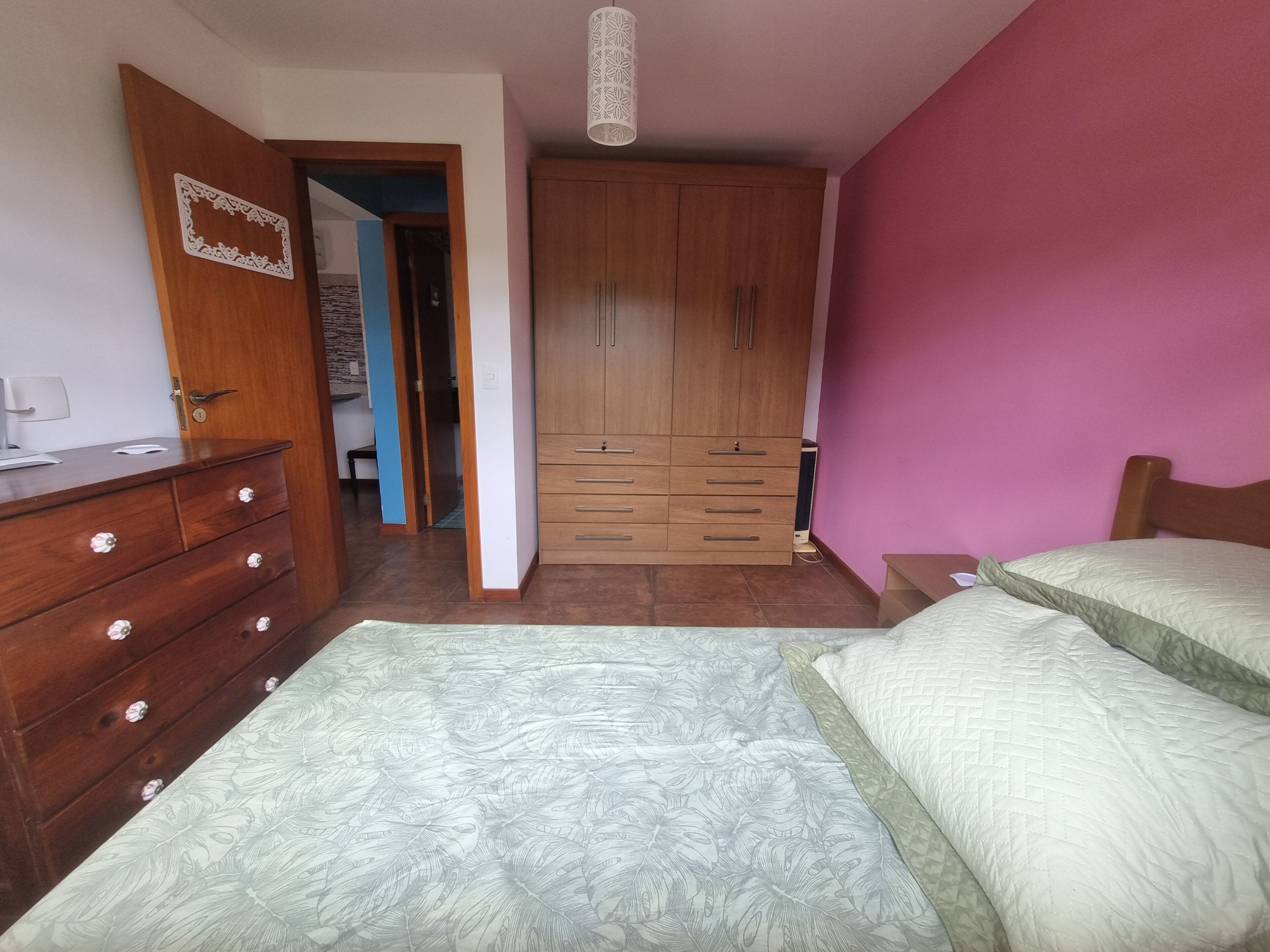 A bedroom with a bed, a dresser, a wardrobe, and a desk.