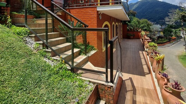 Una casa moderna con una scala in vetro, facciata in mattoni e vista su una montagna.