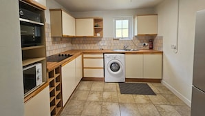 Una cocina compacta con horno integrado, microondas, lavadora y un ventanal.