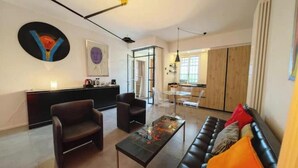 A modern living room with a sofa, chairs, a coffee table, and artwork on the walls. - Hostdomus - Plasch Apartment (Finale Ligure)