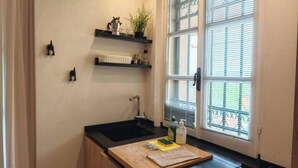 A kitchen with a black sink, wooden countertop, and a window with blinds. - Hostdomus - Plasch Apartment (Finale Ligure)