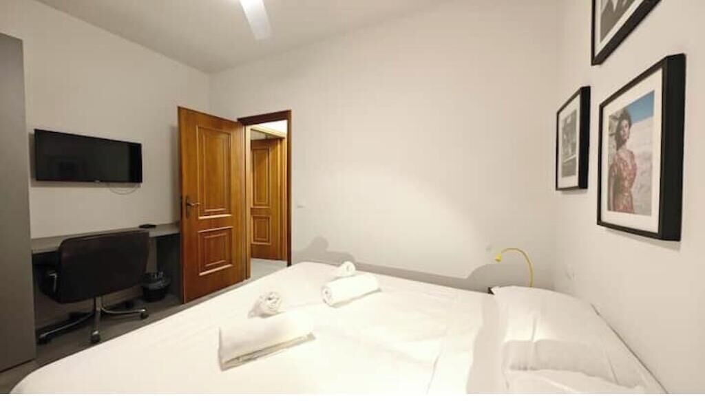 Une chambre d’hôtel comprenant un lit, un bureau avec un ordinateur, une télévision et une porte donnant sur une autre pièce.
