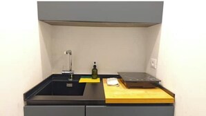 A kitchen with a sink, a bottle, and a cutting board on the countertop. - Hostdomus - Plasch Studio (Finale Ligure)