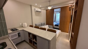 A compact kitchen with a microwave, stove, and coffee maker. - Studio Copacabana Beach 50m (Rio de Janeiro)