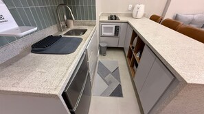 A compact kitchen with a sink, microwave, and a small countertop area. - Studio Copacabana Beach 50m (Rio de Janeiro)