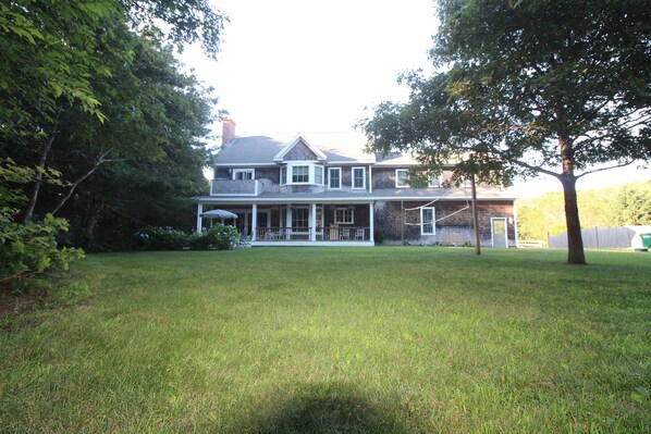 A large two-story house with a front porch, a garage, and a well-maintained lawn. - Main House located on quiet cul-de-sac near town and walking trails to the water (Tisbury)