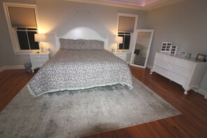 A bedroom with a large bed, bedside tables, a dresser, and a mirror.