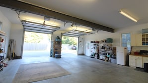Ett garage med en arbetsbänk, hyllor och ett kylskåp.