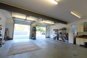 A garage with a workbench, shelves, and a refrigerator. - Main House located on quiet cul-de-sac near town and walking trails to the water (Tisbury)