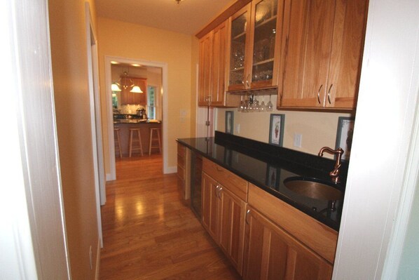 A kitchen with wooden cabinets, a black countertop, and a copper faucet.