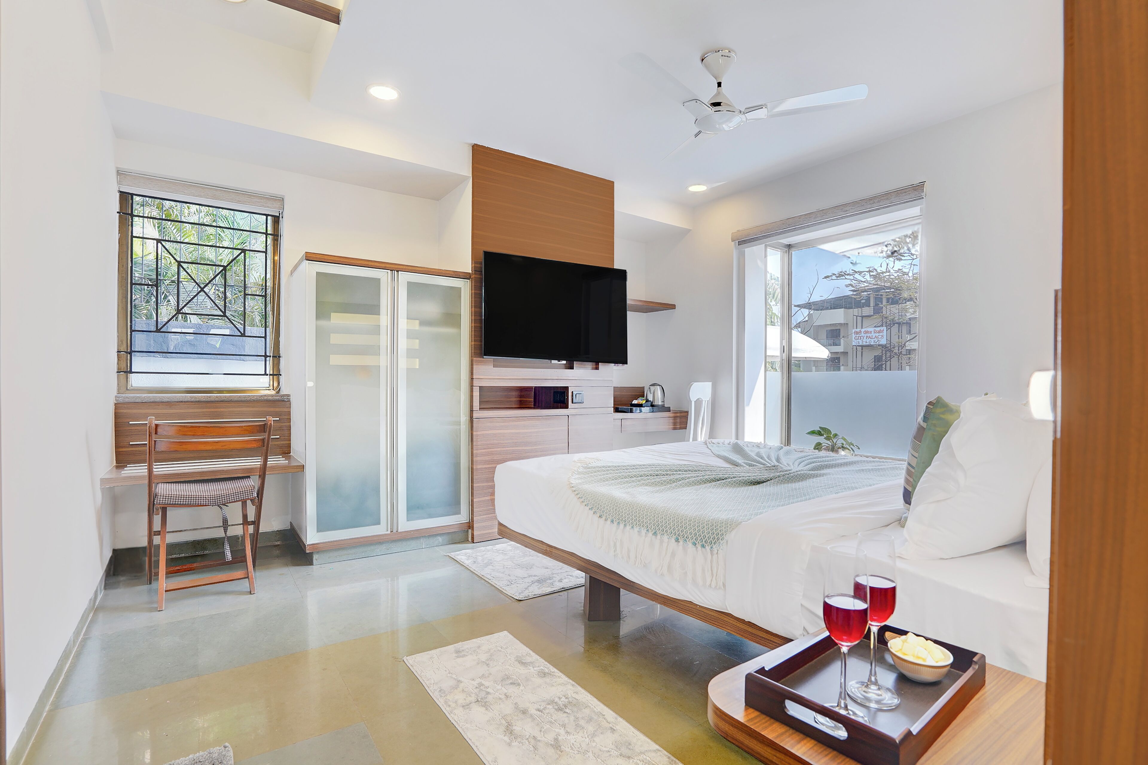 Ein modernes Schlafzimmer mit Bett, Fernseher, Schreibtisch und einer Couch.