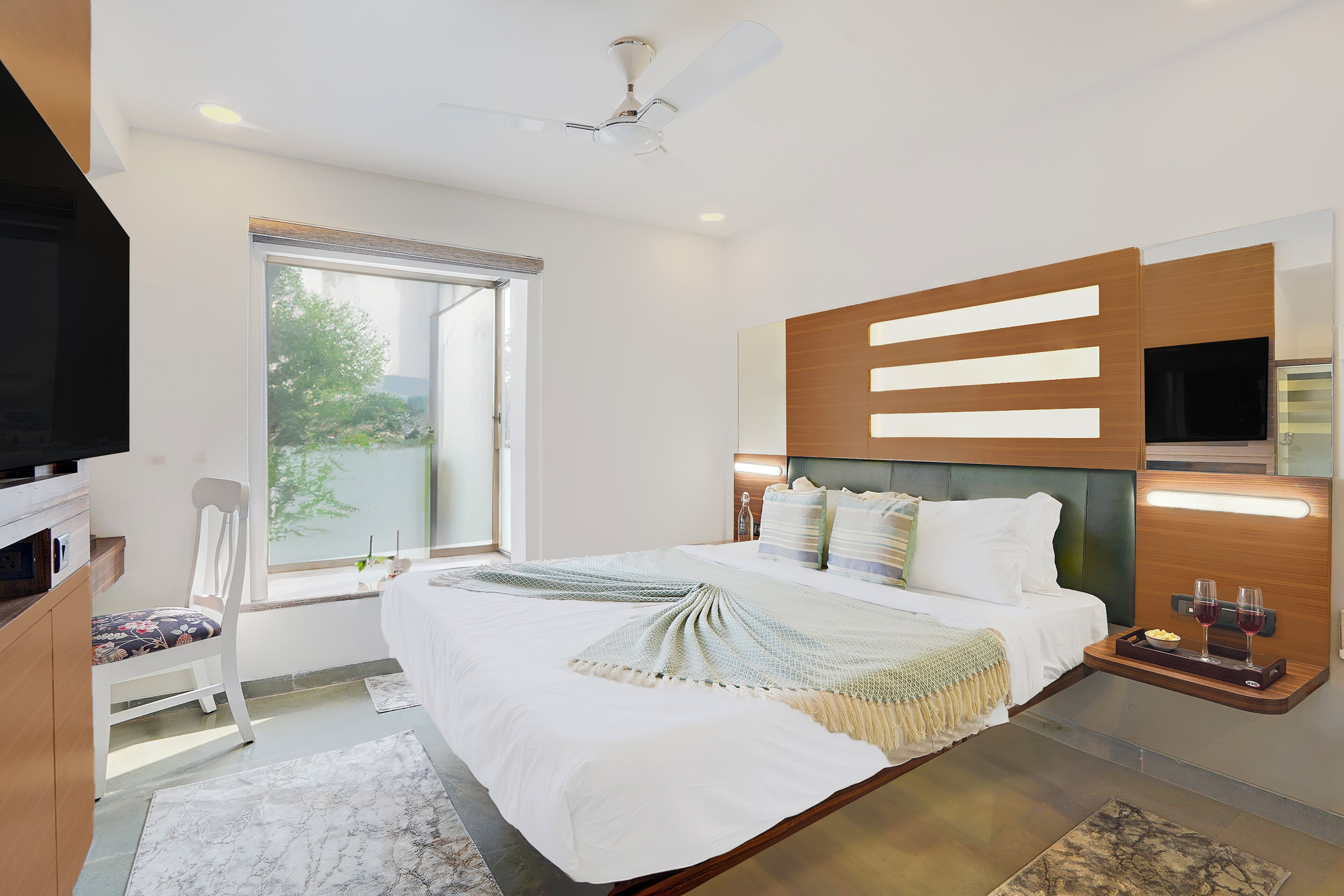 Ein modernes Schlafzimmer mit Bett, Fernseher, Fenster und Deckenventilator.