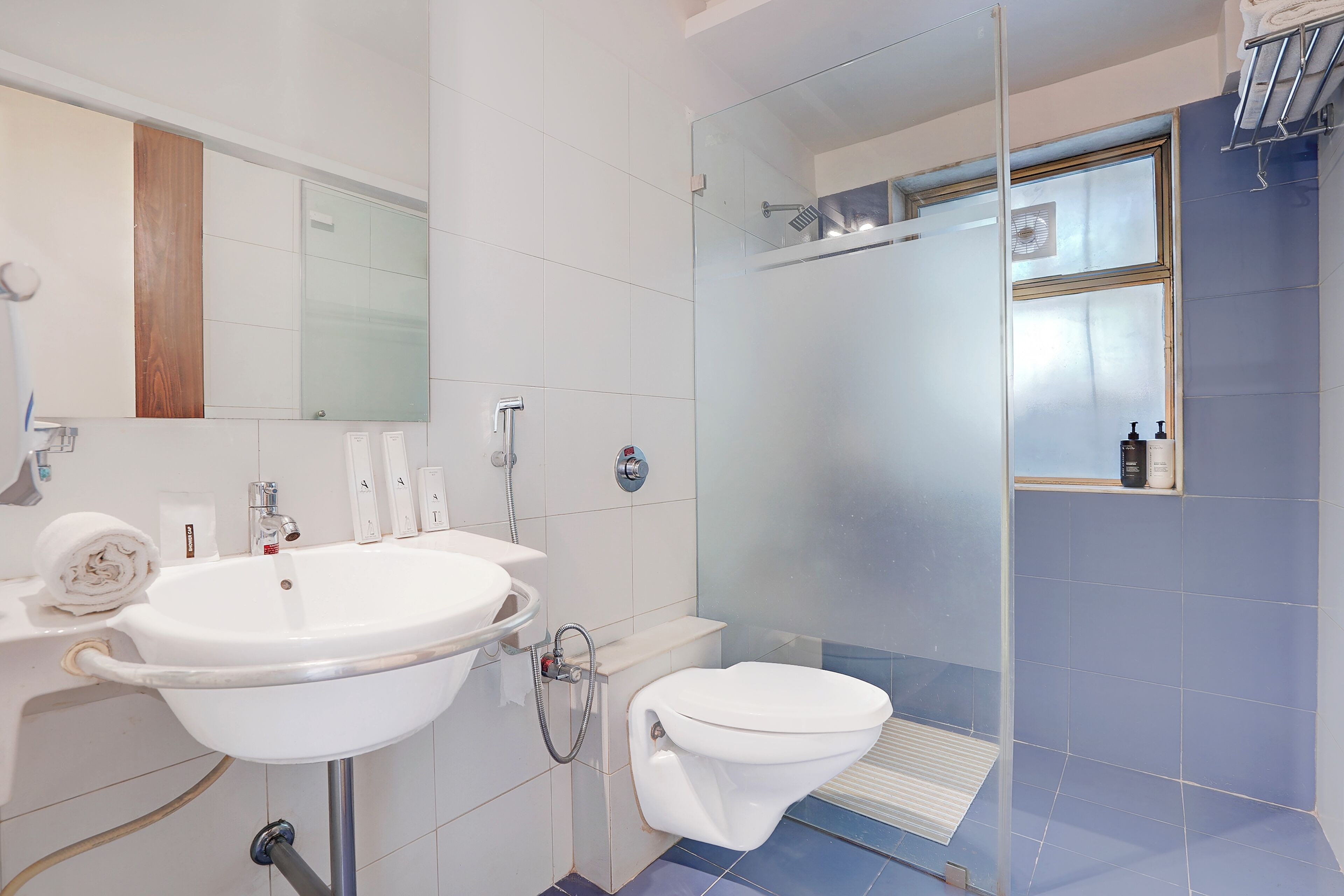 Une salle de bain avec un lavabo blanc, des toilettes et une douche fermée par une paroi de verre.