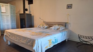 Cama bem arrumada com colcha de tema tropical, uma cadeira e aquecedor fixado na parede.