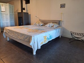 A neatly made bed with a tropical-themed bedspread, a chair, and a wall-mounted heater. - Loft 4 people 80 m² on the Presqu'île de Giens (Var) Vacation rental (Hyères)
