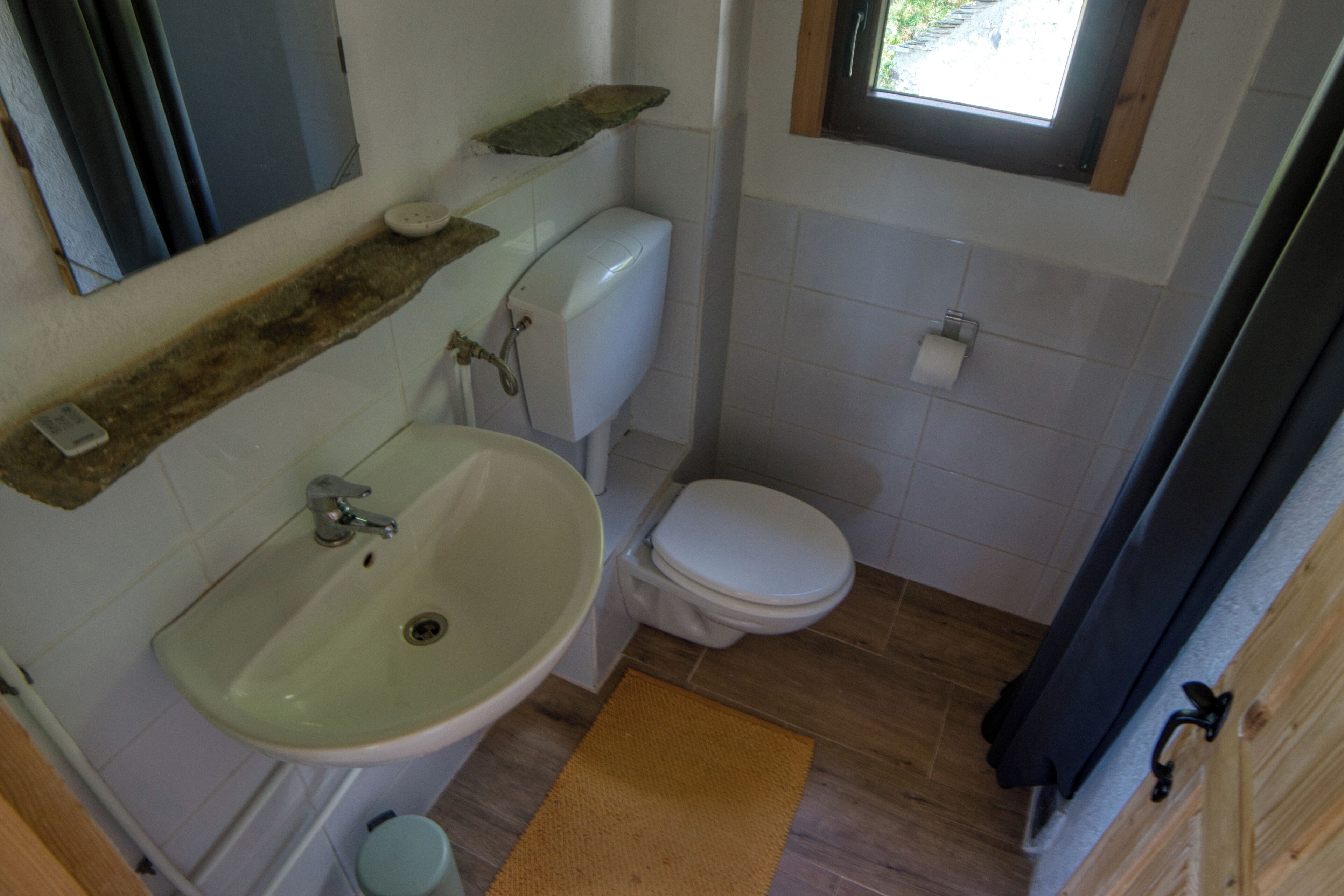 A bathroom with a sink, toilet, and window.