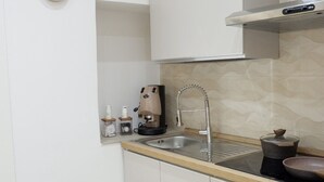 Una cocina con un lavabo, estufa, horno y un reloj en la pared.