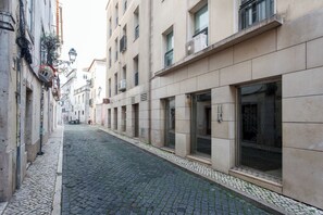 Eine enge Kopfsteinpflasterstraße, gesäumt von Gebäuden mit großen Fenstern und Klimaanlagen.