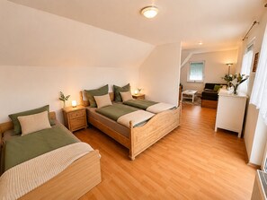 A bedroom with two beds, a small desk, a chair, and a window. - Casa Piccola - cozy and charming. Close to Bamberg. (Strullendorf)